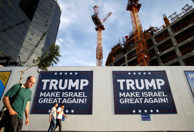 people-walk-past-signs-bearing-the-name-of-u-s-president-elect-republican-donald-trump-in-tel-aviv-israel